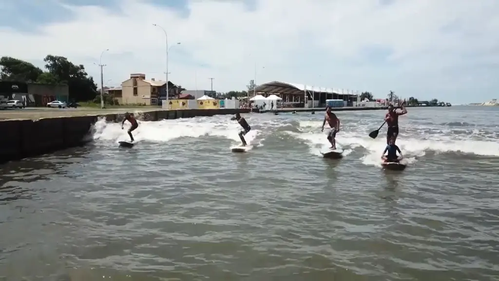Surfistas aproveitam a pororoca no Rio Tramandaí com a ressaca do mar