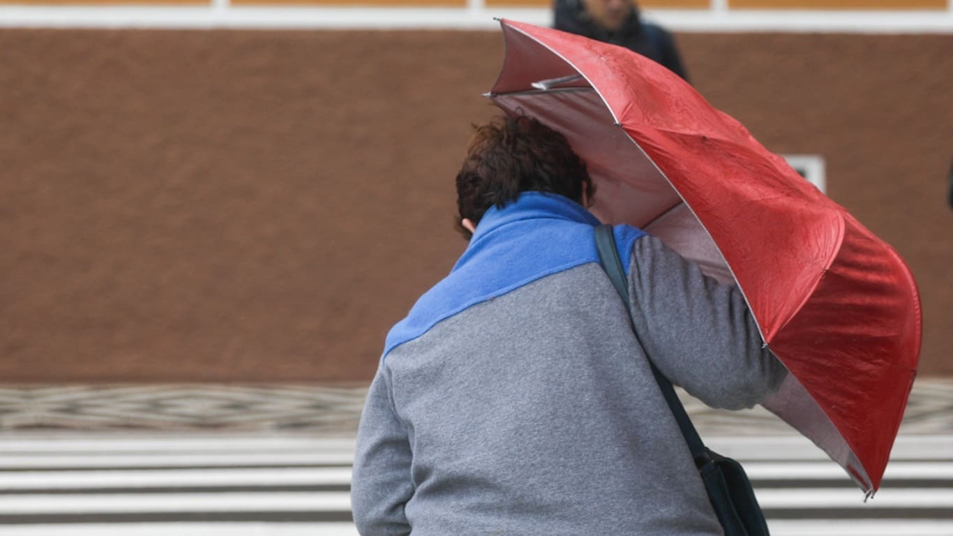 Foto mostra mulher na rua em Porto Alegre com chuva, vento e frio 