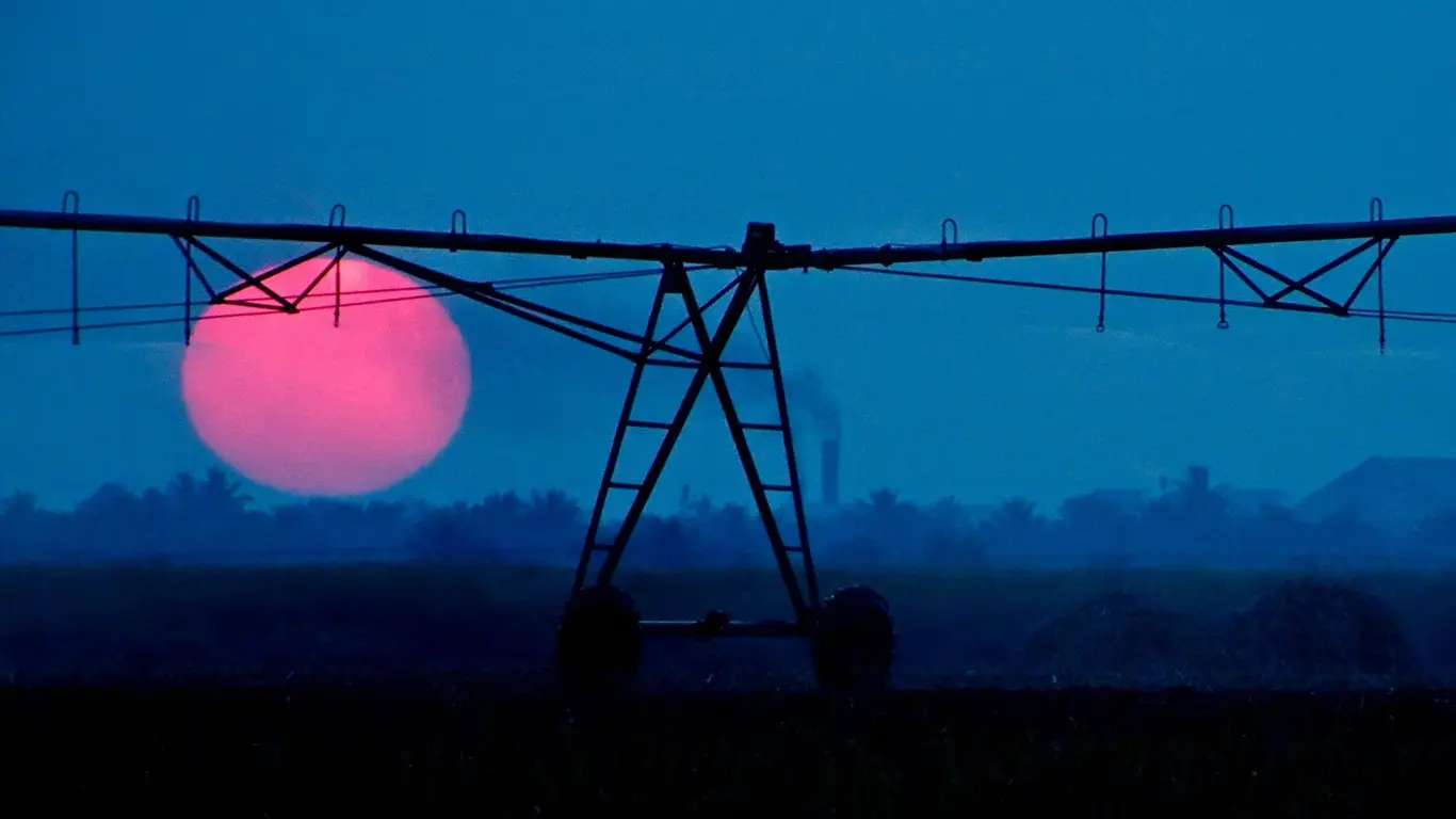 Foto mostra agricultura e pivô em fim de tarde com sol onda de calor