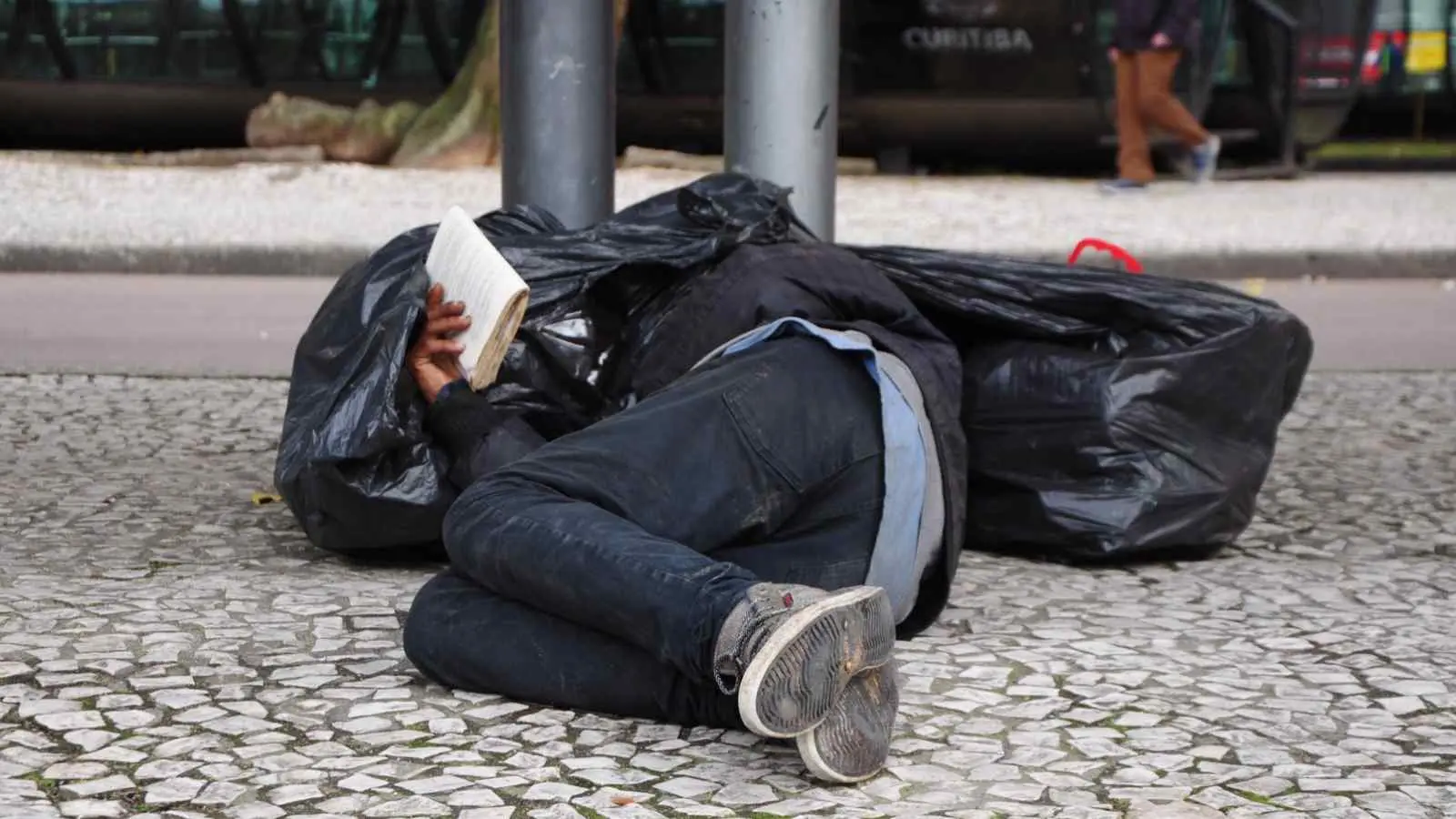 Foto mostra morador de rua em noite de frio