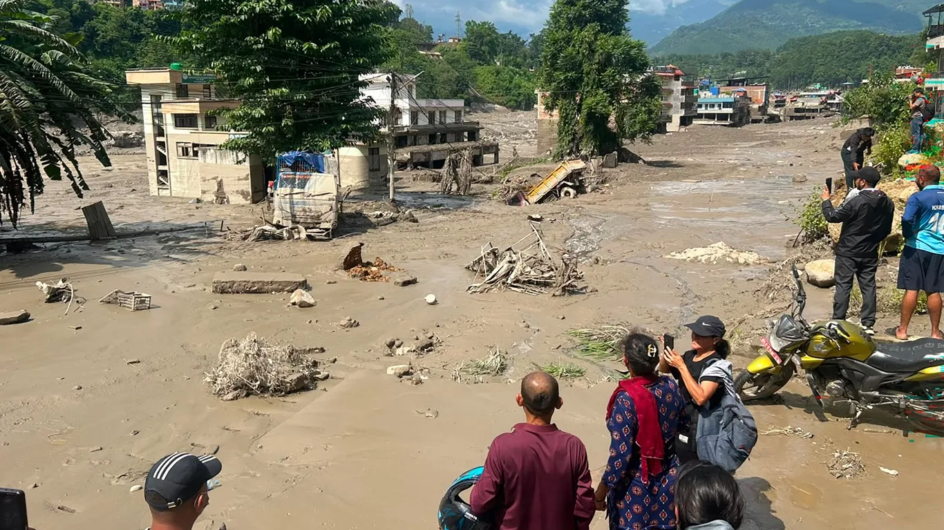 Moradores observam casas parcialmente submersas pela água barrenta após enchentes repentinaspor possível GLOF em Trishuli Bazar, no distrito de Nuwakot, Nepal